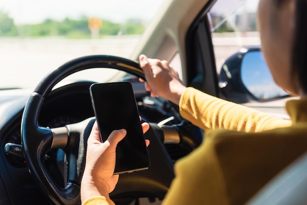 Foto sección media de una mujer usando un teléfono inteligente mientras conduce un coche