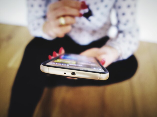 Foto sección media de una mujer usando un teléfono móvil en casa