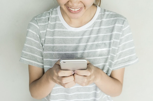 Sección media de una mujer usando un teléfono móvil contra un fondo gris