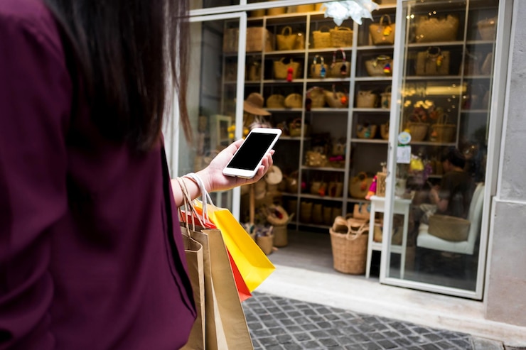 Foto sección media de una mujer usando un teléfono móvil contra una tienda