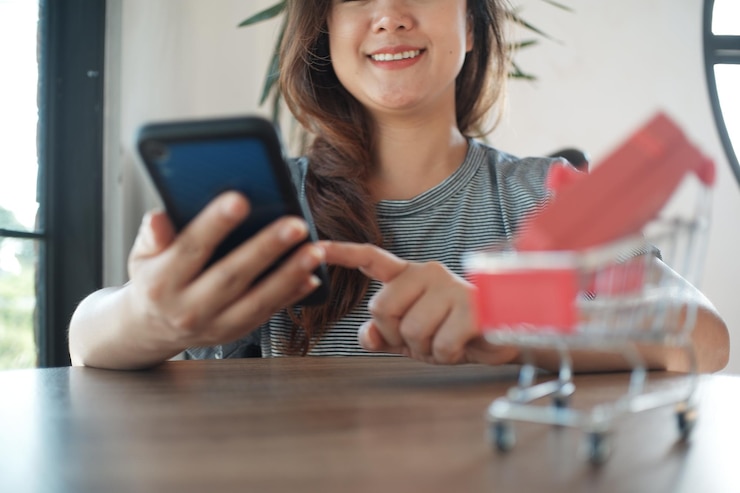 Foto sección media de una mujer usando el teléfono móvil en la mesa en casa