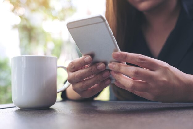 Sección media de una mujer usando el teléfono móvil en la mesa