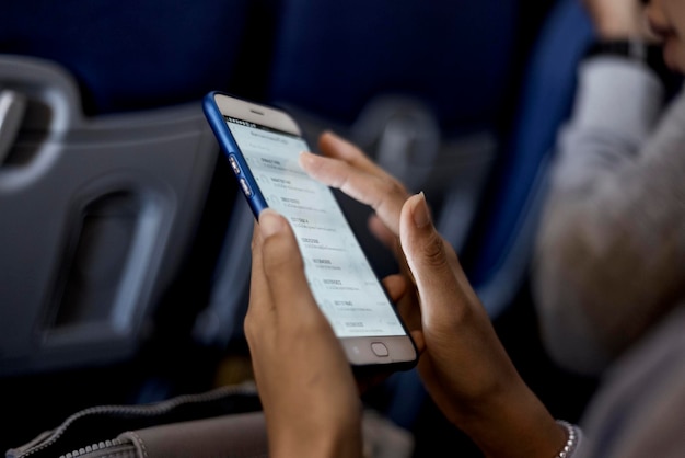 Sección media de una mujer usando un teléfono móvil mientras está sentada en un avión