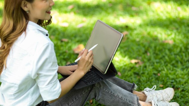 Sección media de una mujer usando un teléfono móvil mientras está sentada en el césped