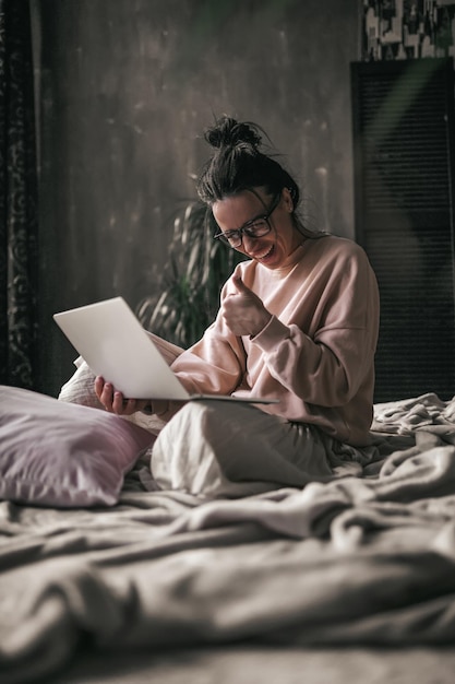 Sección media de una mujer usando el teléfono móvil mientras se relaja en la cama