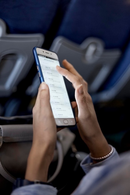 Foto sección media de una mujer usando un teléfono móvil mientras está sentada en un avión