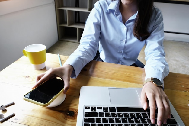 Foto sección media de una mujer usando el teléfono móvil mientras está sentada en la mesa