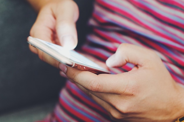 Sección media de una mujer usando un teléfono móvil