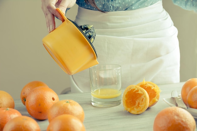 Foto sección media de una mujer vertiendo jugo de naranja en la mesa