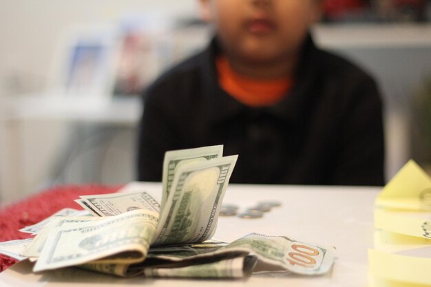 Foto sección media de un niño con papel moneda en la mesa