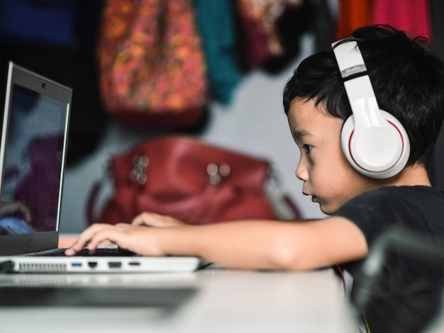 Sección media de un niño usando una computadora portátil en casa