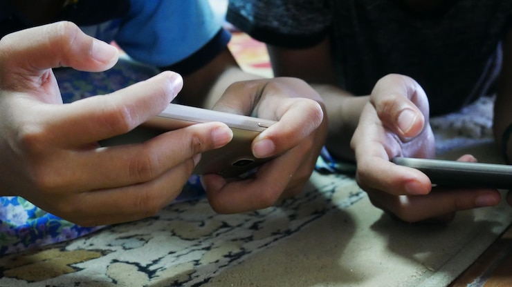 Foto sección media de niños que usan teléfonos móviles en la cama