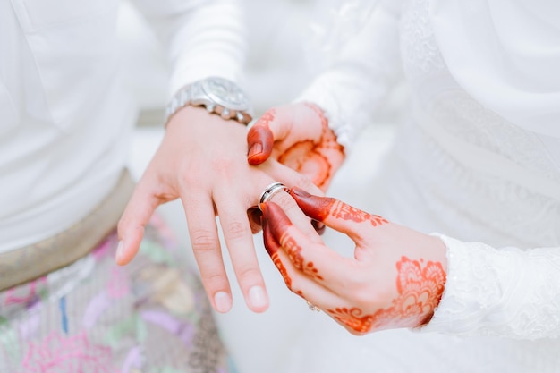 Sección media de la novia poniendo el anillo en el dedo del novio durante la ceremonia de la boda