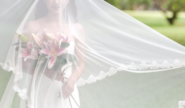 Foto sección media de la novia sosteniendo flores mientras está de pie al aire libre