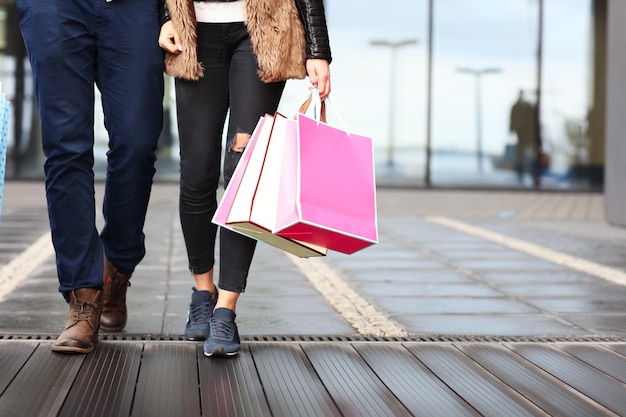 Sección media de la pareja con bolsas de compras en la ciudad