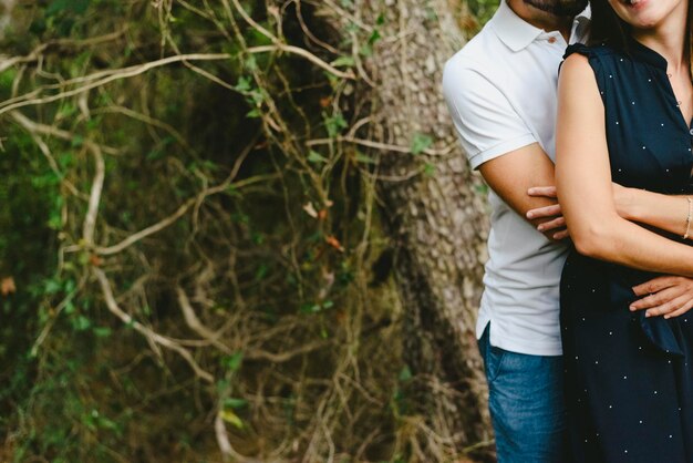 Foto sección media de una pareja de pie contra un árbol