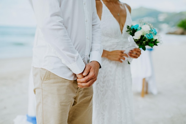 Foto sección media de una pareja de recién casados de pie en la playa