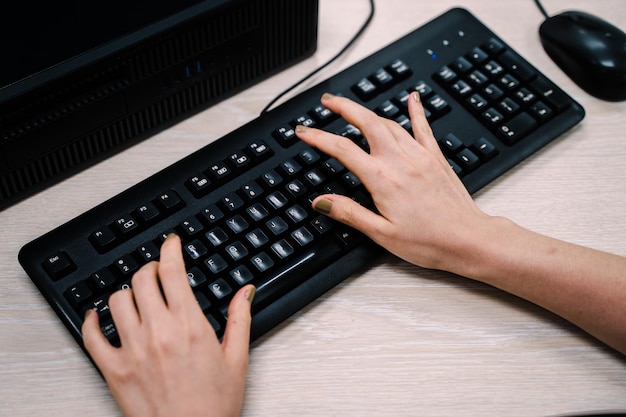 Sección media de una persona escribiendo usando el teclado en la mesa
