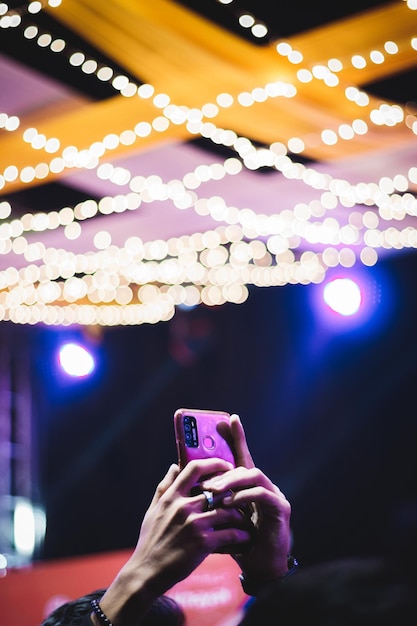 Foto sección media de una persona fotografiando un teléfono móvil iluminado por la noche