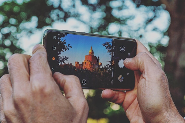 Sección media de una persona fotografiando con un teléfono móvil san luca bologna