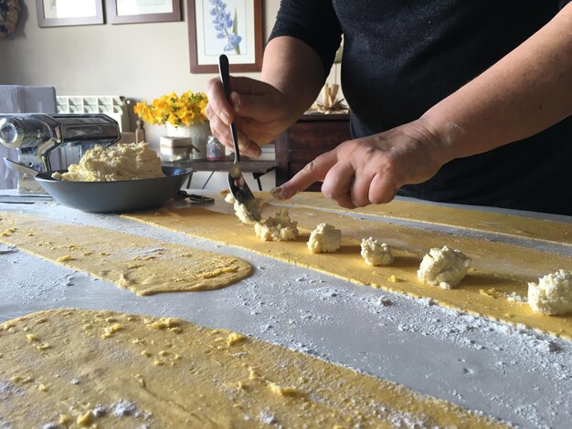 Foto sección media de una persona preparando pasta en casa