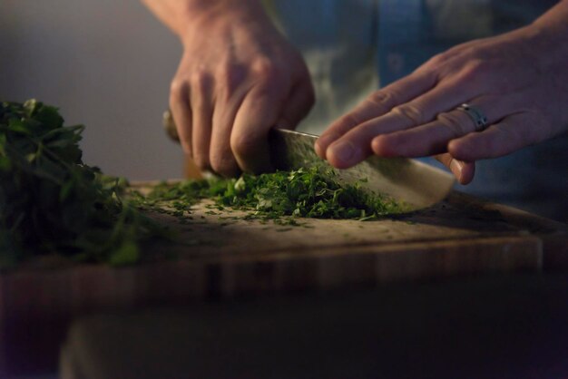 Sección media de una persona que prepara alimentos en la tabla de cortar