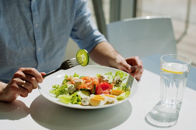 Sección media de una persona que sostiene un tenedor en un restaurante