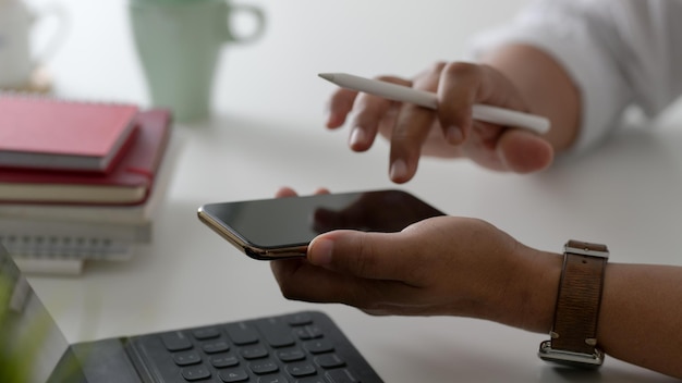 Foto sección media de una persona que usa un teléfono móvil en la mesa