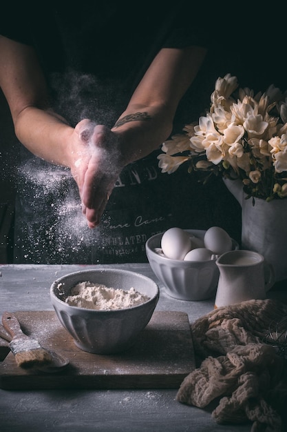 Sección media de una persona salpicando harina en el mostrador de la cocina