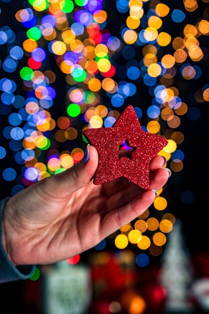 Foto sección media de una persona sosteniendo decoraciones navideñas iluminadas