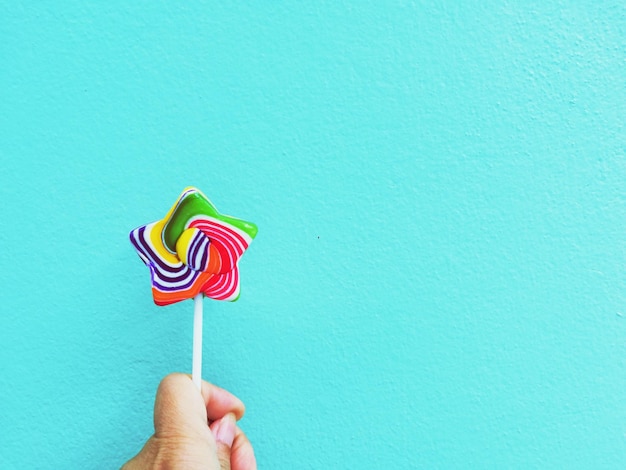 Foto sección media de una persona sosteniendo un helado contra el cielo azul