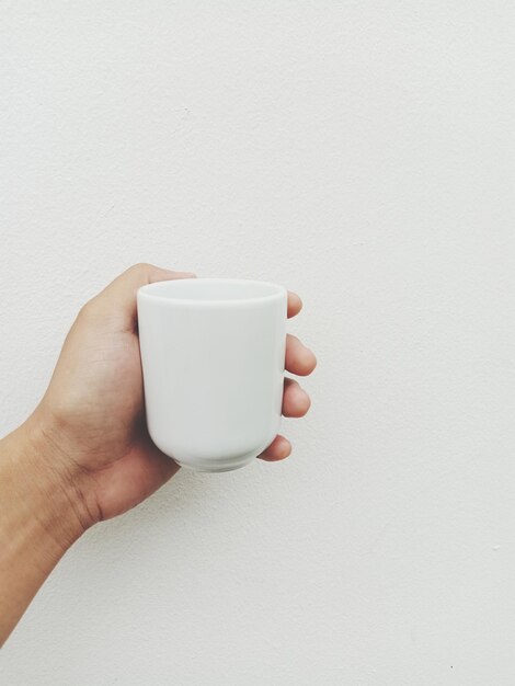 Sección media de una persona sosteniendo una taza de café contra un fondo blanco