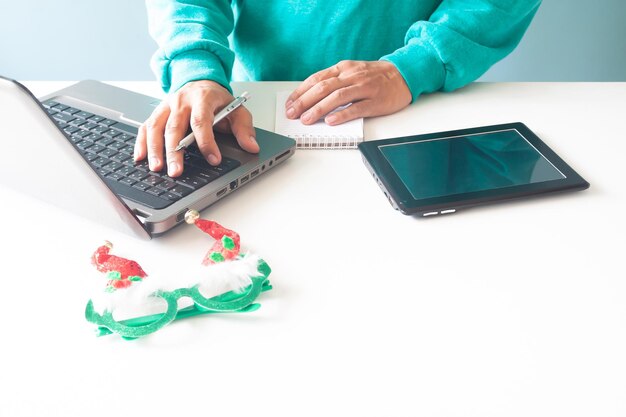 Sección media de una persona usando una computadora portátil con decoraciones navideñas en la mesa en casa
