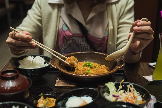 Foto sección media de primer plano de una mujer comiendo con palillos en la mesa