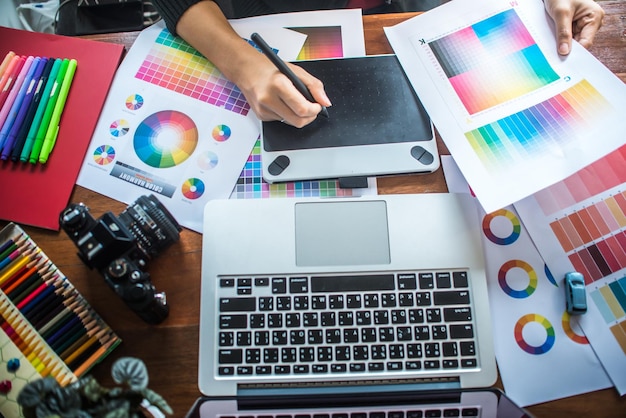 Sección media de un profesional de diseño que utiliza una tableta gráfica en la mesa