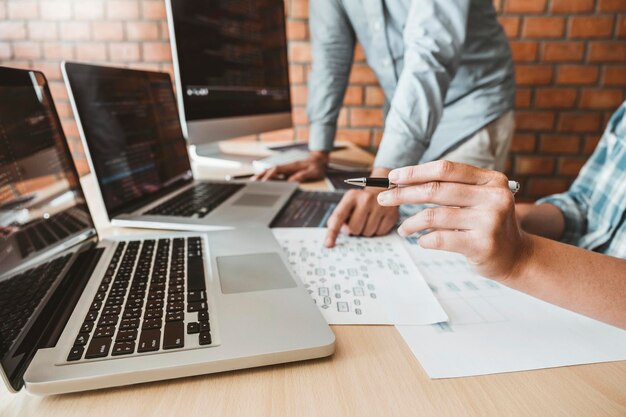 Sección media de programadores codificando en computadoras en el escritorio de la oficina
