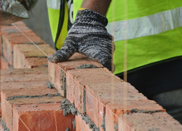 Sección media de un trabajador colocando ladrillos en un sitio de construcción