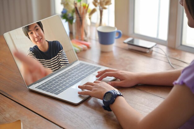 Foto sección media de videoconferencia de una mujer a través de una computadora portátil en la mesa de casa