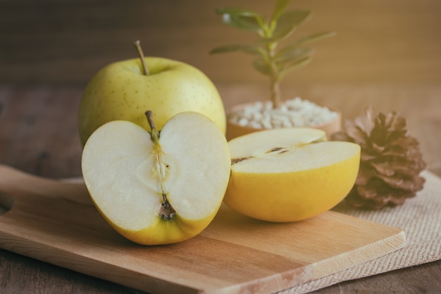 La sección representativa de las manzanas de oro frescas de Shinano de Japón puso la tabla de madera bajo luz del sol.