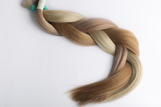 Secções de cabelo feminino para extensão trançadas na cauda, sobre fundo branco.