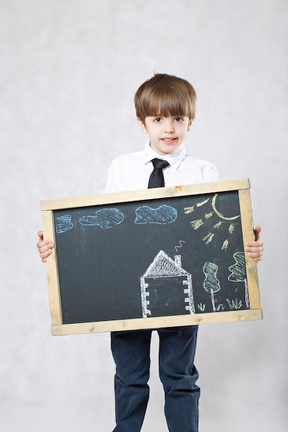 Sechs Jahre alter Junge mit abgebildetem Haus auf einer Holzoberfläche. Nahaufnahme
