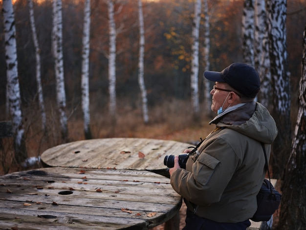 Sechzigjähriger Mann, der einen Herbstspaziergang während der Quarantäne allein mit einer Kamera genießt