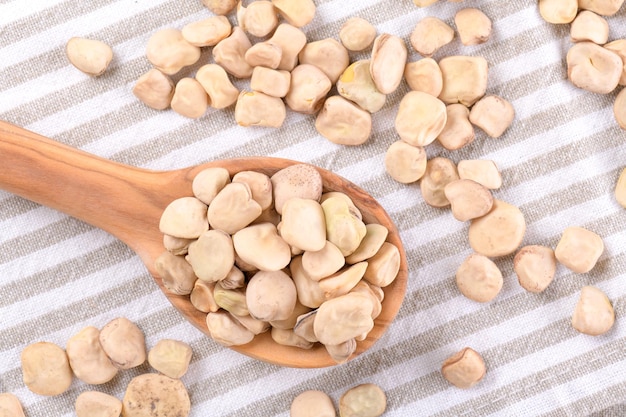 Seco Cicerchia ou ervilha indiana em uma colher de pau em um guardanapo de algodão, close-up, alimentos sem glúten. Leguminosas conhecidas como Lathyrus Sativus, Chickling Ervilhaca, Blue Sweet Pea feita na Puglia, vista superior