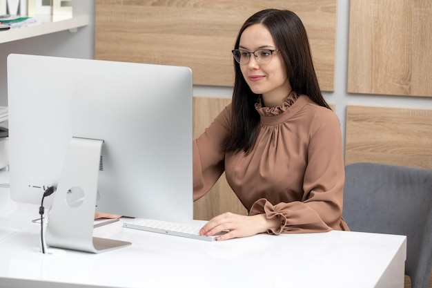 Secretaria joven que trabaja en la oficina en la computadora