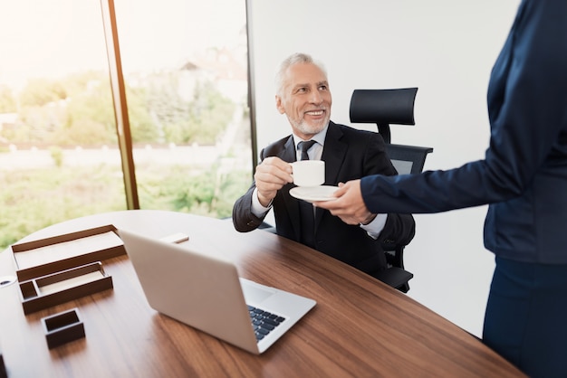 La secretaria le trajo a su jefe una taza de café.