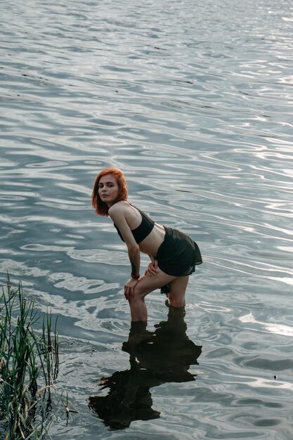 Seductora chica pelirroja sexy en lencería y blusa vintage posando en el lago al atardecer para revistas