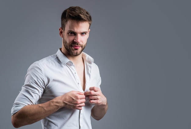 Seduzindo você cara não barbeado em estilo casual cabeleireiro masculino e barbearia tendência de beleza masculina homem barbudo com pêlos faciais de cerdas sensuais e cuidados com a pele homem bonito usa camisa branca espaço para cópia