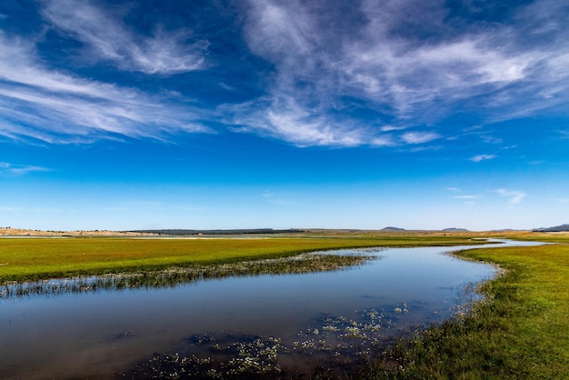 See Afnourir in Marokko. Der Himmel spiegelt sich im stillen Wasser eines sumpfigen Sees