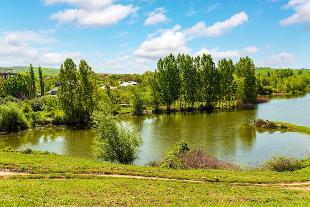 See bei einem Dorf mit grünen Hügeln