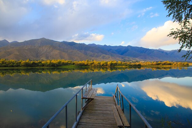 See in den Bergen Alte hölzerne Pier zum Angeln Schöne Natur Reflexion von Wolken und Bergen im blauen Wasser Kirgisistan See IssykKul